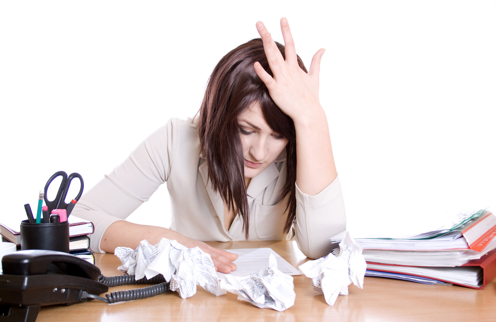 Woman looking stressed with crumpled papers on her desk