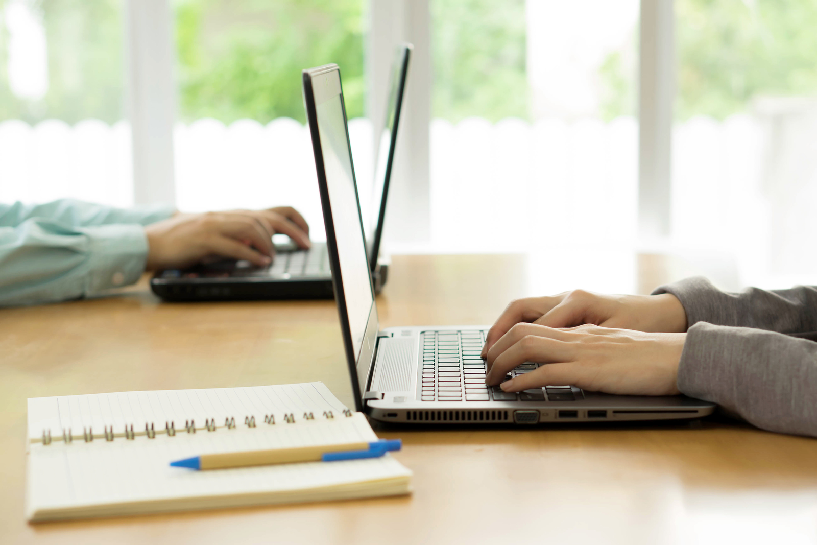 two business people sitting at laptops at opposite sides of a table